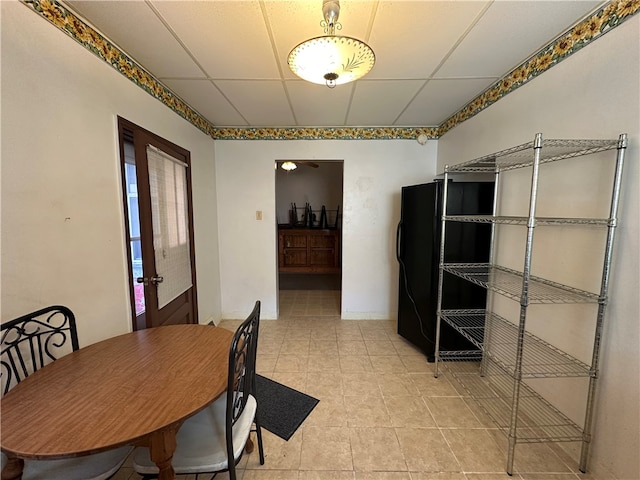 unfurnished dining area with light tile patterned floors, a paneled ceiling, and french doors