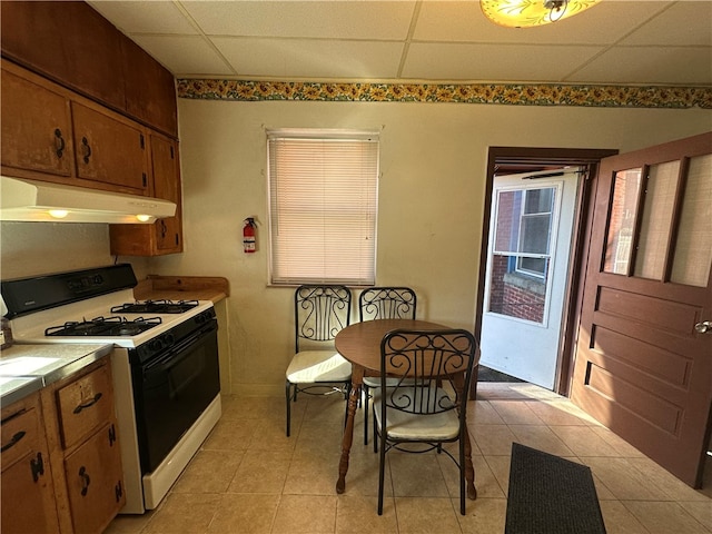 kitchen with a paneled ceiling, tile counters, light tile patterned floors, and white range with gas stovetop