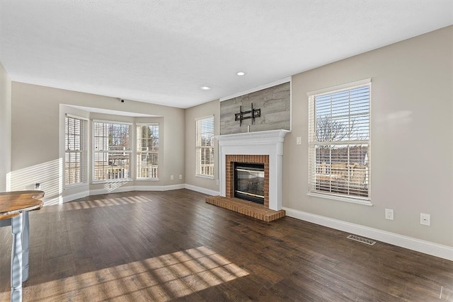 unfurnished living room featuring a fireplace, dark wood-type flooring, and a textured ceiling