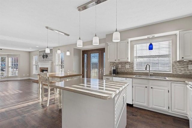 kitchen featuring dishwasher, a center island, white cabinetry, and sink