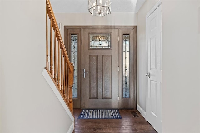 foyer entrance featuring a chandelier, dark wood-type flooring, and a textured ceiling