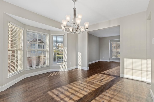 unfurnished dining area featuring a chandelier, dark hardwood / wood-style flooring, and a healthy amount of sunlight