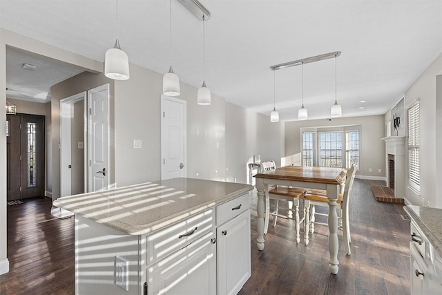 kitchen featuring a center island, dark wood-type flooring, white cabinets, and hanging light fixtures