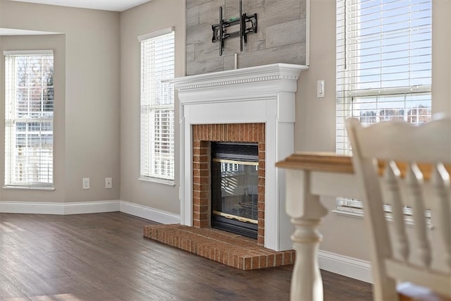 unfurnished living room featuring a brick fireplace and dark wood-type flooring