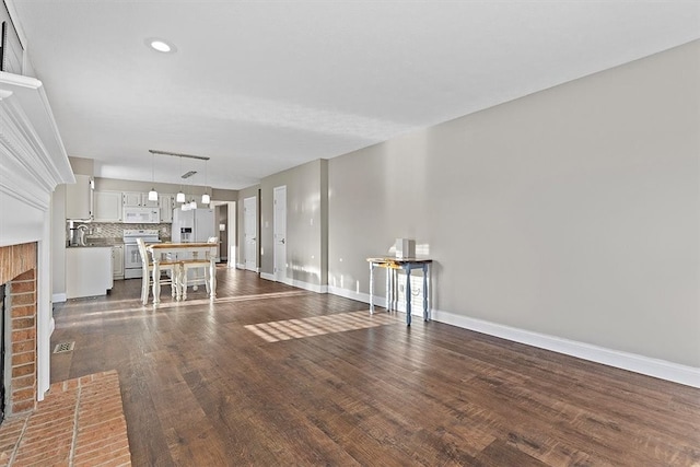 unfurnished living room with dark hardwood / wood-style flooring and a brick fireplace