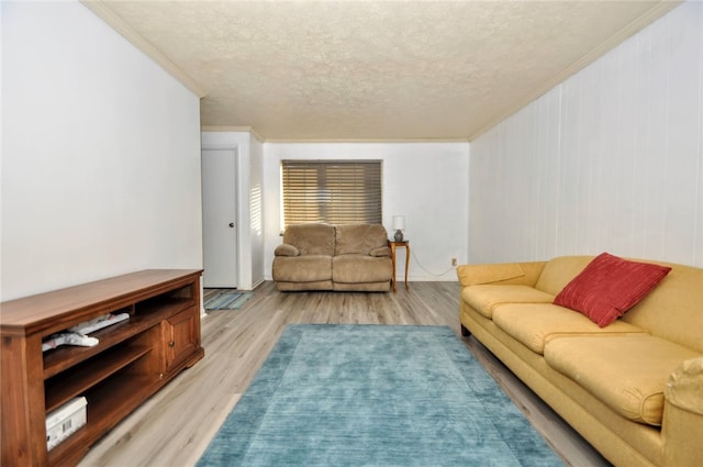 living room featuring a textured ceiling, light hardwood / wood-style floors, and crown molding