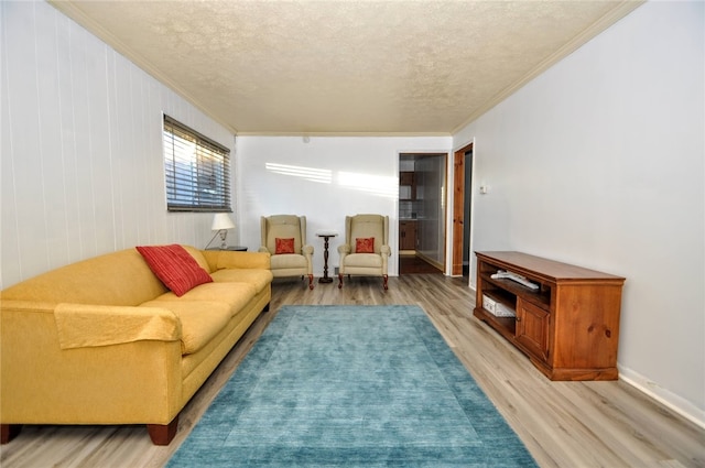 living room featuring light hardwood / wood-style flooring, ornamental molding, and a textured ceiling