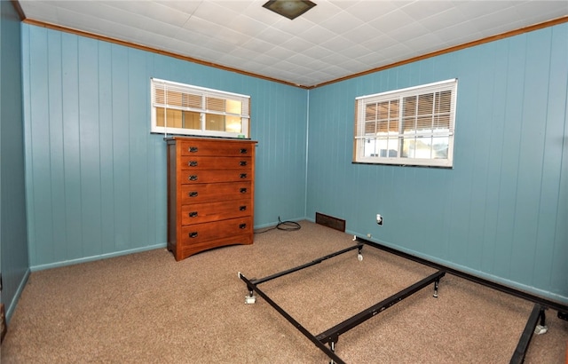 bedroom featuring light colored carpet, ornamental molding, and wood walls