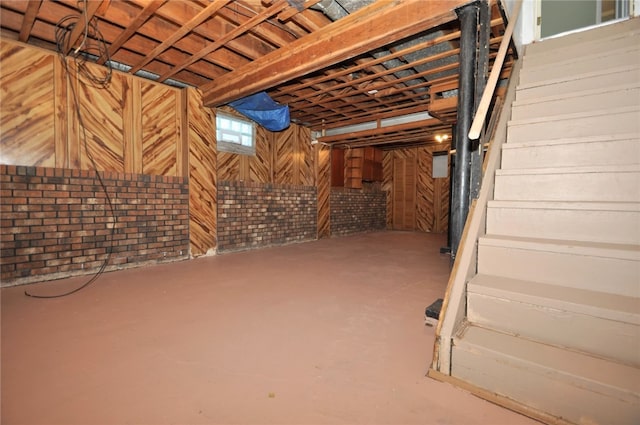 basement with wood walls and brick wall