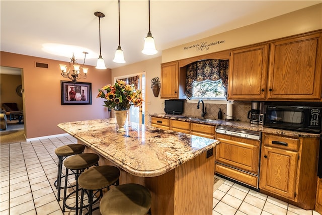 kitchen featuring paneled dishwasher, sink, decorative light fixtures, a center island, and light tile patterned flooring