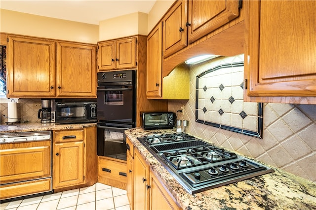 kitchen with light stone countertops, light tile patterned floors, backsplash, and black appliances