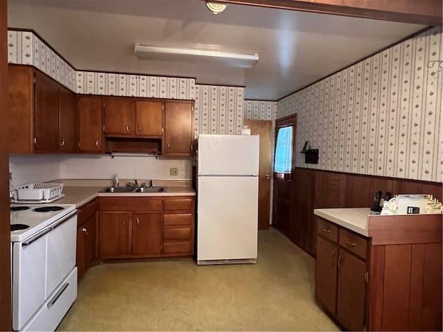 kitchen with white appliances, light colored carpet, wood walls, and sink