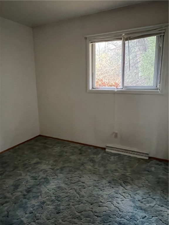 carpeted empty room featuring baseboard heating