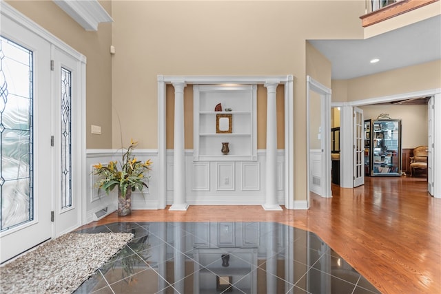 foyer entrance featuring ornate columns and dark wood-type flooring