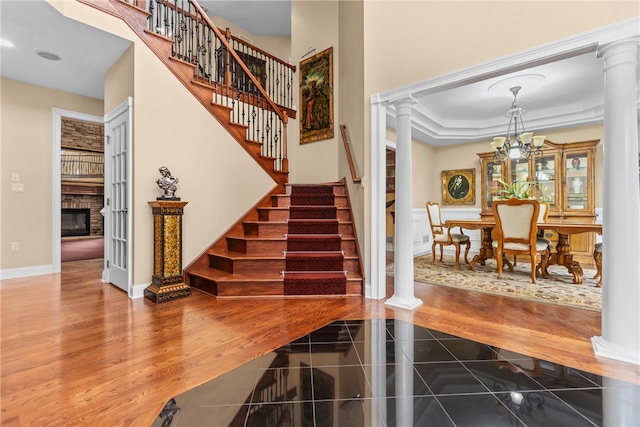 stairs featuring hardwood / wood-style flooring, ornate columns, a notable chandelier, and crown molding