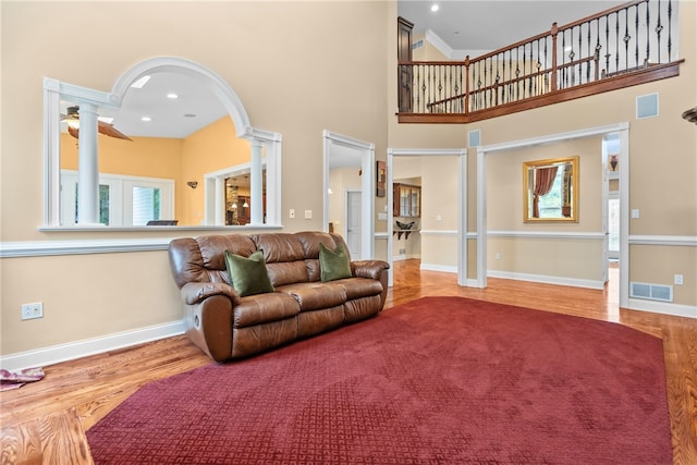 living room with ornate columns, wood-type flooring, and a high ceiling