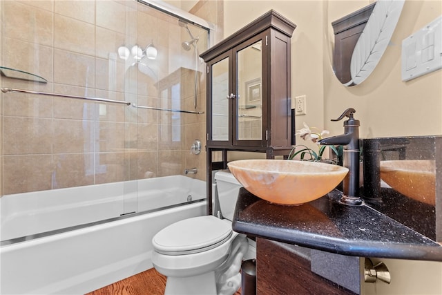 full bathroom featuring hardwood / wood-style flooring, toilet, sink, and shower / bath combination with glass door