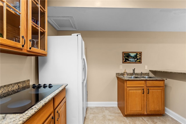 kitchen featuring sink, white fridge with ice dispenser, light tile patterned floors, and stone countertops