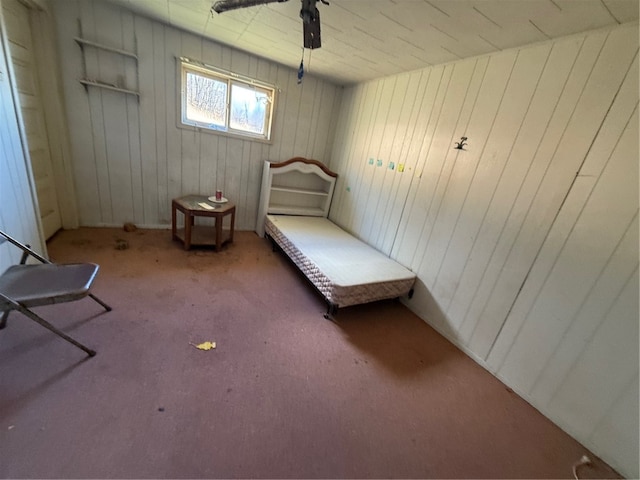 unfurnished bedroom featuring carpet flooring, ceiling fan, and wood walls