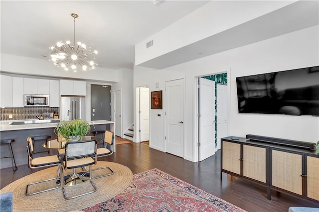 interior space featuring appliances with stainless steel finishes, tasteful backsplash, a notable chandelier, white cabinets, and hanging light fixtures