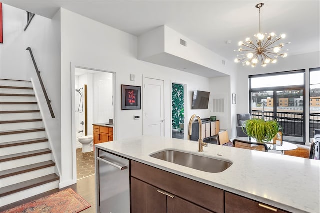 kitchen featuring dishwasher, sink, decorative light fixtures, light stone countertops, and a notable chandelier