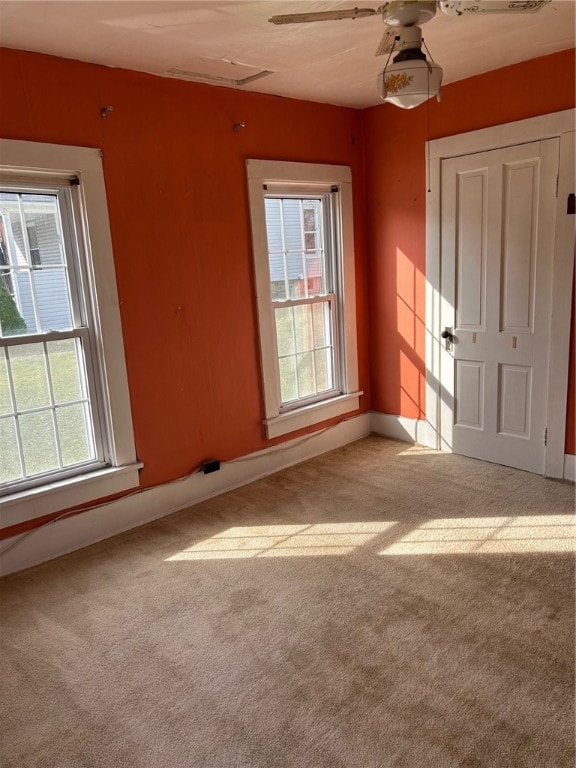 spare room featuring ceiling fan, plenty of natural light, and carpet