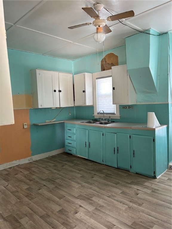 kitchen featuring sink, green cabinetry, ceiling fan, light wood-type flooring, and white cabinetry