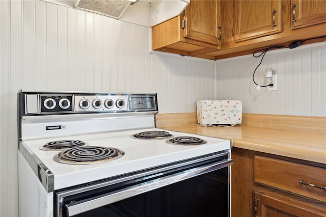 kitchen with extractor fan, white electric stove, and wooden walls