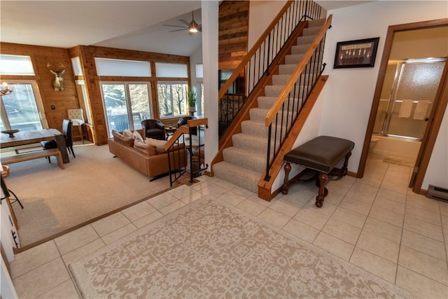 living room featuring light tile patterned floors, ceiling fan with notable chandelier, lofted ceiling, and wood walls