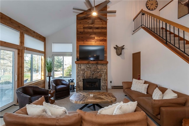 living room featuring carpet flooring, high vaulted ceiling, a wealth of natural light, and a stone fireplace