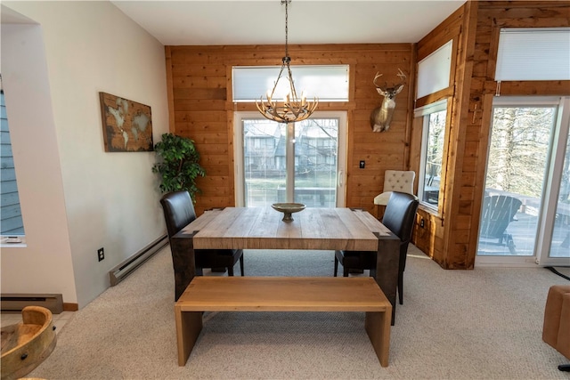 carpeted dining room with a chandelier, wooden walls, and a baseboard heating unit