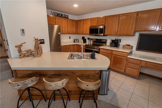 kitchen featuring a breakfast bar, stainless steel appliances, kitchen peninsula, and sink