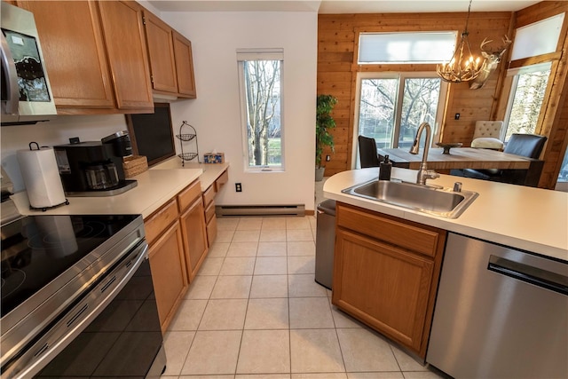 kitchen with sink, hanging light fixtures, stainless steel appliances, a notable chandelier, and wooden walls