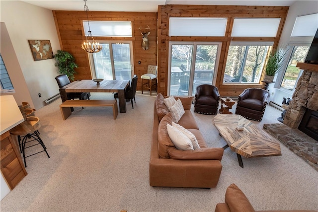 carpeted living room with wood walls, a healthy amount of sunlight, a fireplace, and an inviting chandelier