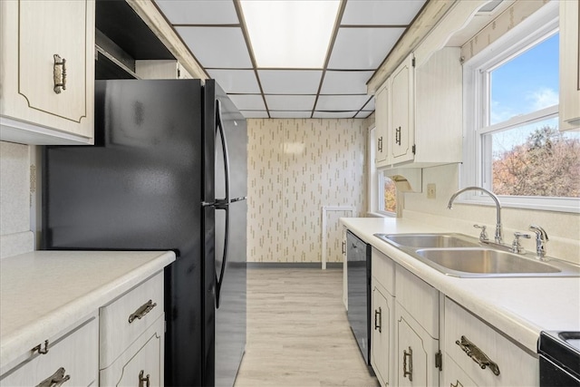 kitchen featuring a paneled ceiling, sink, black appliances, and light wood-type flooring