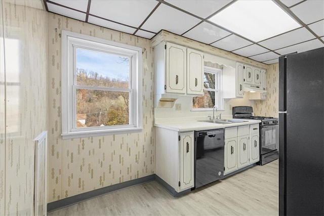 kitchen featuring premium range hood, light hardwood / wood-style floors, a paneled ceiling, white cabinets, and black appliances