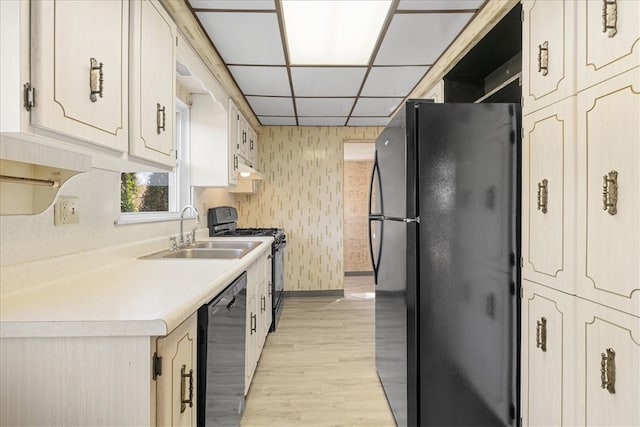 kitchen featuring a paneled ceiling, sink, black appliances, and light wood-type flooring