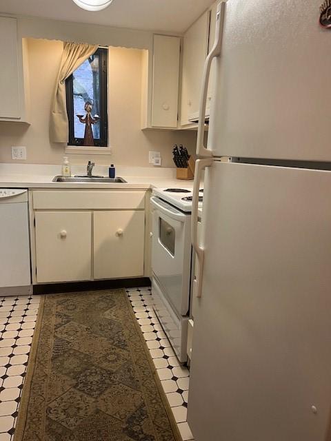 kitchen with white cabinetry, sink, and white appliances