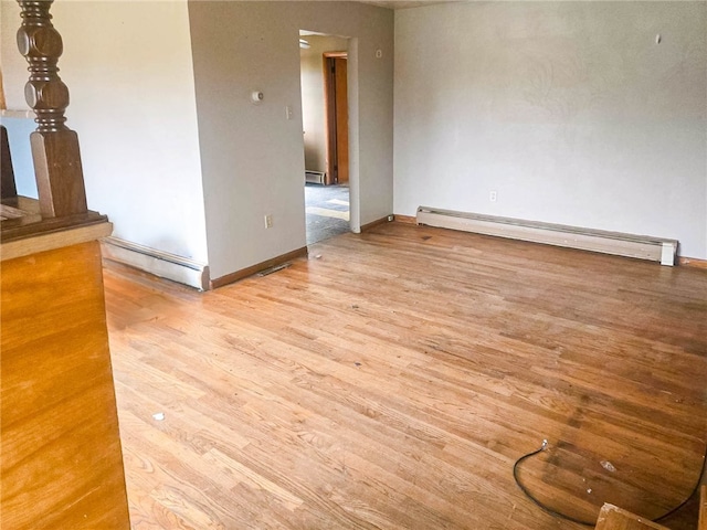 empty room with baseboard heating and light wood-type flooring