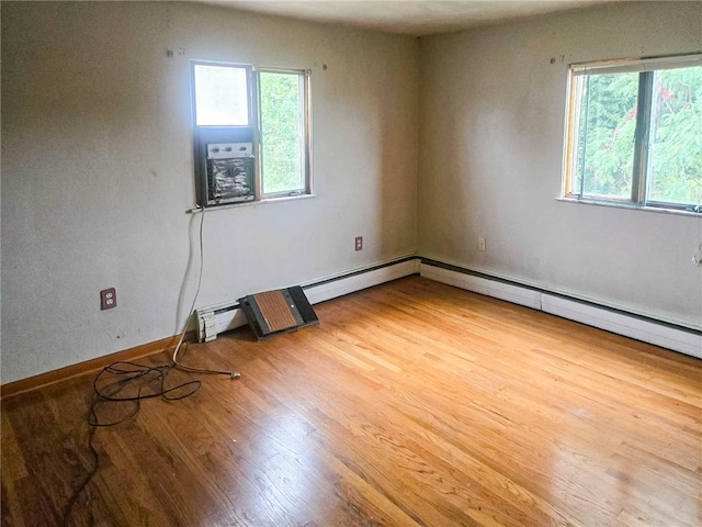 unfurnished room with baseboard heating, plenty of natural light, and light hardwood / wood-style floors