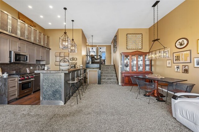 kitchen featuring backsplash, a kitchen bar, a kitchen island, dark carpet, and appliances with stainless steel finishes