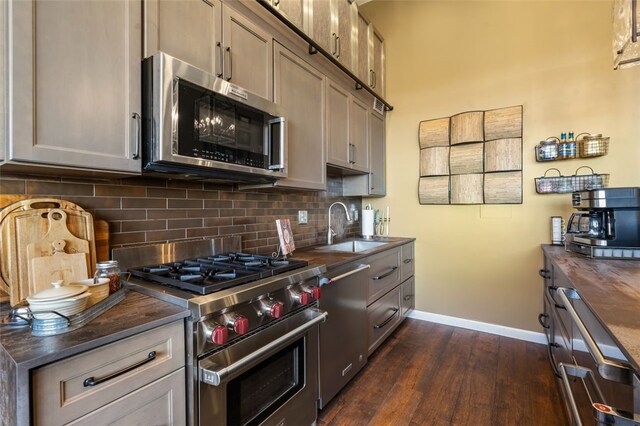 kitchen with sink, dark wood-type flooring, backsplash, butcher block countertops, and appliances with stainless steel finishes