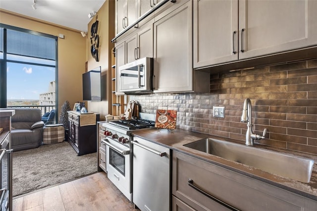 kitchen with backsplash, sink, stainless steel appliances, and light wood-type flooring