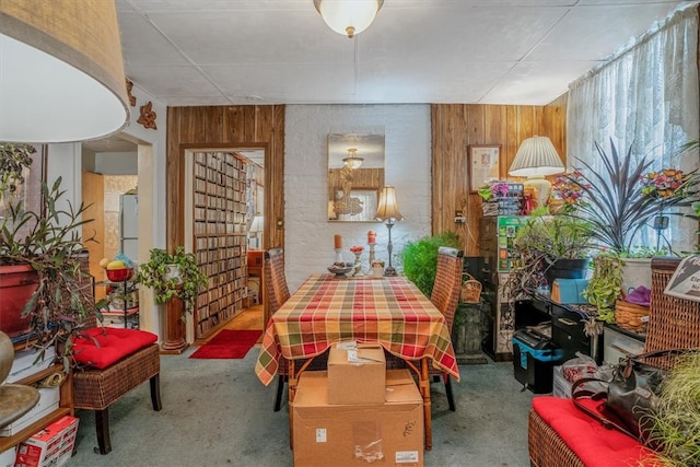 dining space with carpet flooring and wooden walls