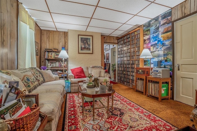 carpeted living room with a paneled ceiling and wooden walls