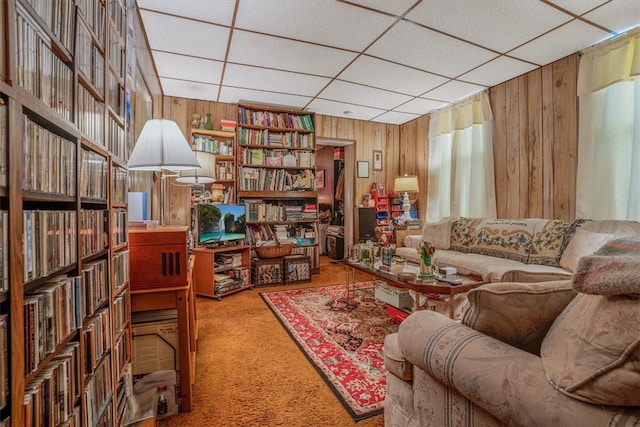 sitting room featuring a drop ceiling, wood walls, and carpet flooring