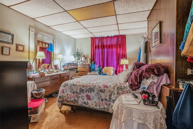 bedroom featuring a drop ceiling and carpet