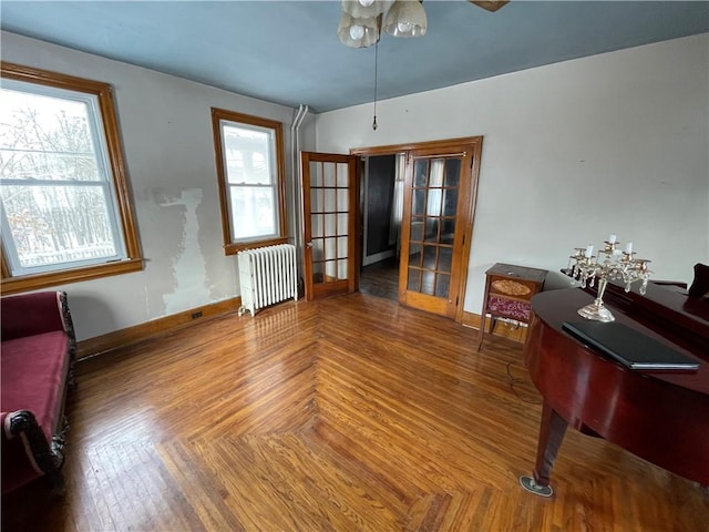 interior space with parquet floors, a wealth of natural light, french doors, and radiator