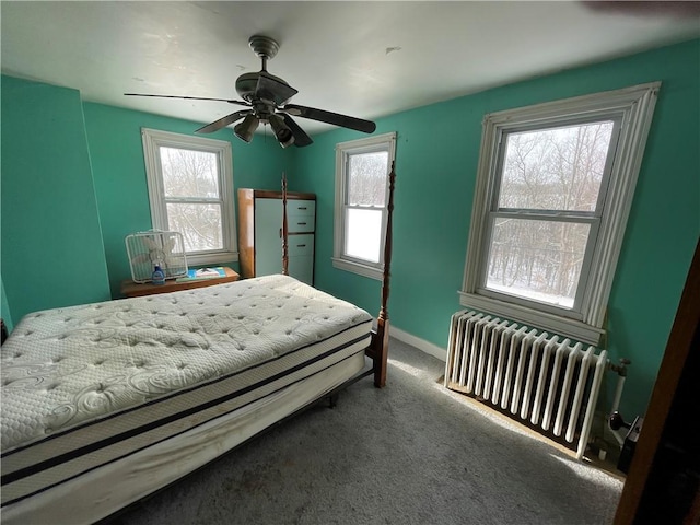 carpeted bedroom featuring radiator heating unit, multiple windows, and ceiling fan