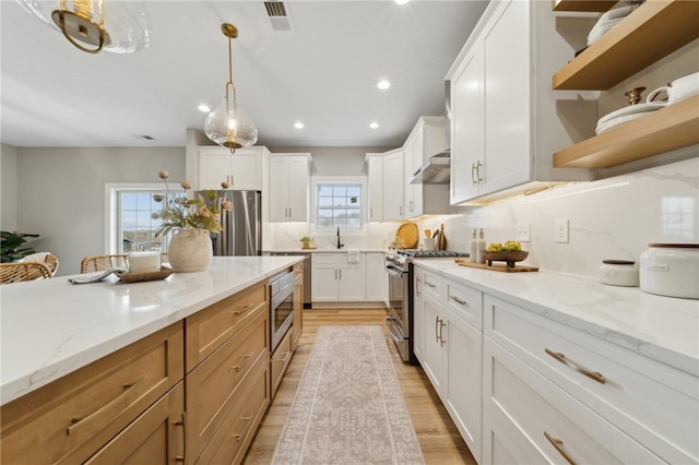 kitchen with white cabinets, a healthy amount of sunlight, light stone counters, and stainless steel appliances